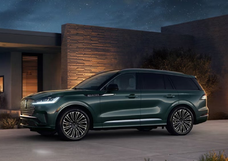 A green 2027 Lincoln Aviator® SUV is parked outside a contemporary home. | Doral Lincoln in Doral FL