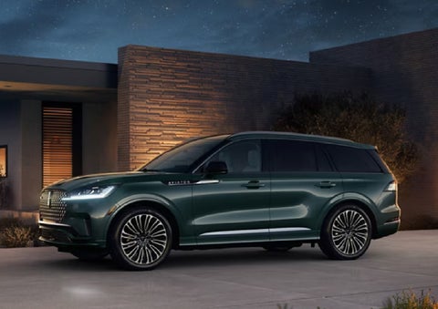 A green 2027 Lincoln Aviator® SUV is parked outside a contemporary home. | Doral Lincoln in Doral FL