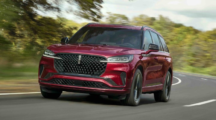 A 2027 Lincoln Aviator® SUV is being driven on a country road | Doral Lincoln in Doral FL