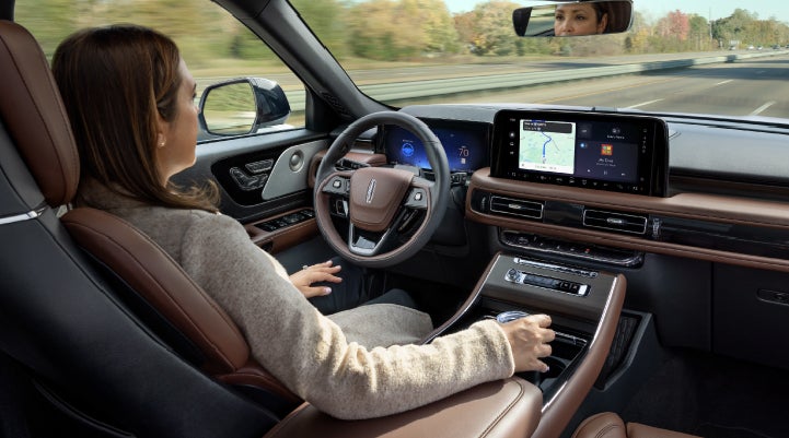 A 2027 Lincoln Aviator® SUV is being driven hands-free on a highway lined with trees. | Doral Lincoln in Doral FL