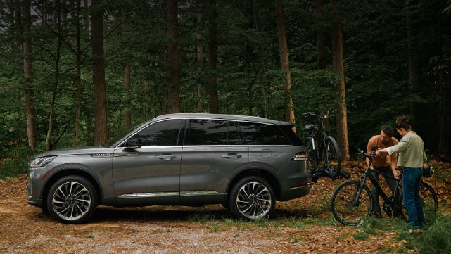A father and son load e-bikes on a bike rack attached to a 2027 Lincoln Aviator® SUV. | Doral Lincoln in Doral FL